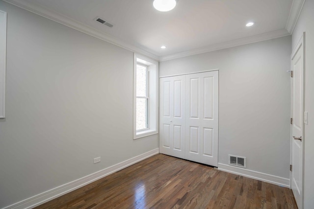 unfurnished bedroom with crown molding, dark wood-type flooring, and a closet