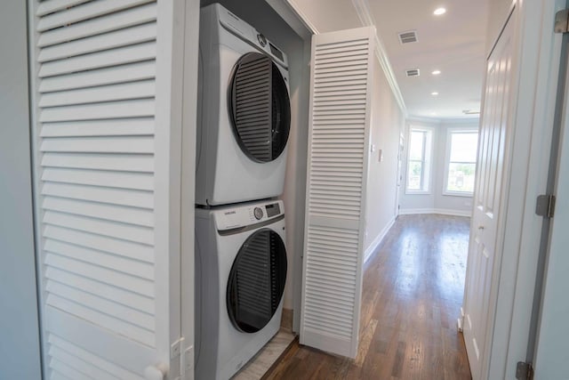 laundry room with stacked washer / dryer, dark wood-type flooring, and ornamental molding