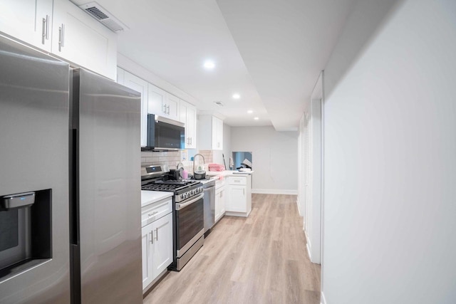 kitchen with white cabinets, decorative backsplash, light wood-type flooring, and stainless steel appliances