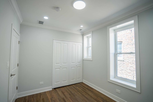 unfurnished bedroom with a closet, dark hardwood / wood-style flooring, and ornamental molding