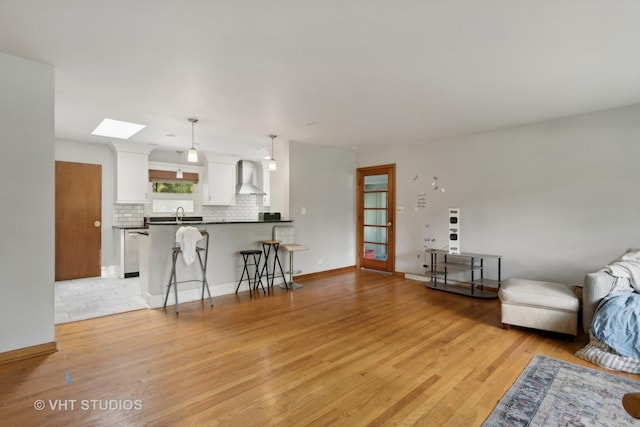 living room with sink, a skylight, and light hardwood / wood-style floors