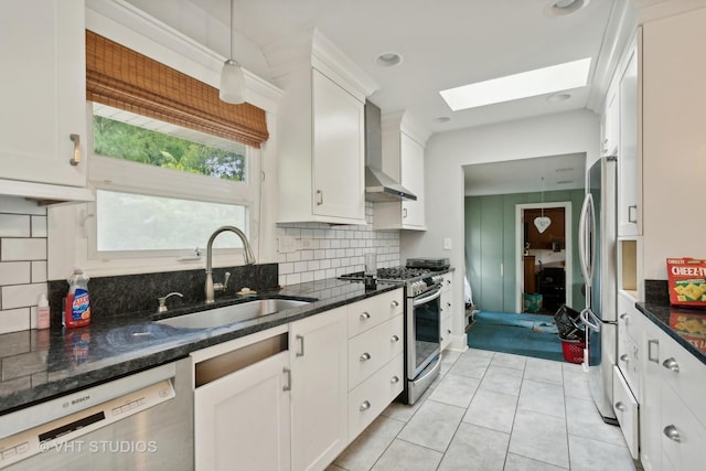 kitchen with stainless steel appliances, white cabinetry, sink, and wall chimney range hood