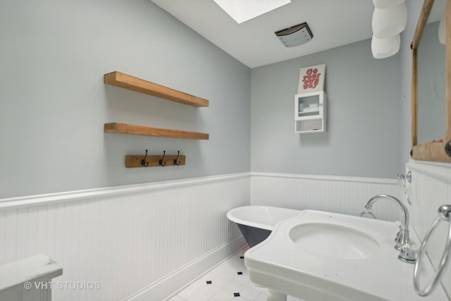 bathroom with a bathing tub, sink, and a skylight