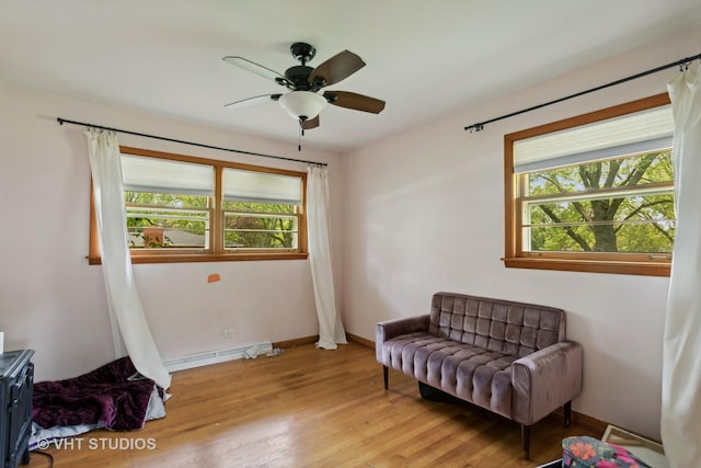 sitting room featuring a baseboard radiator, light hardwood / wood-style floors, and ceiling fan