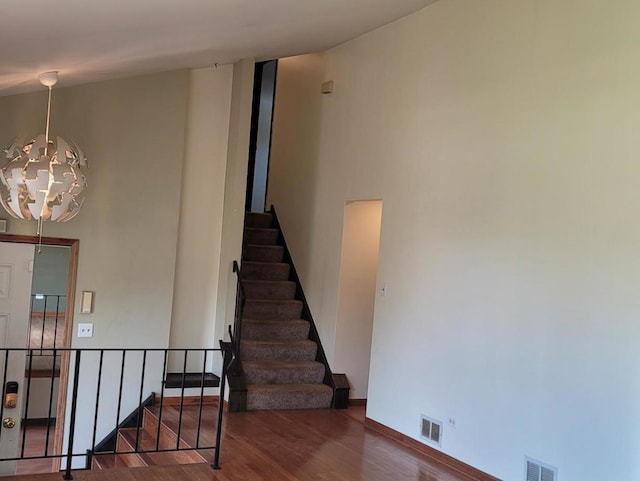 stairway with hardwood / wood-style flooring and a notable chandelier