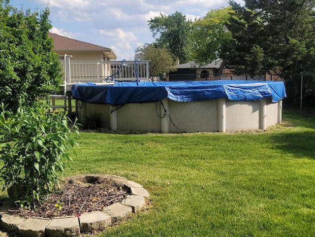 view of pool featuring a wooden deck, a yard, and a fire pit