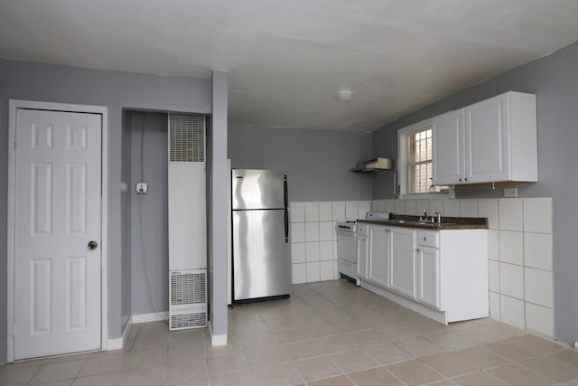 kitchen featuring white cabinets, light tile patterned floors, stainless steel refrigerator, and white gas range