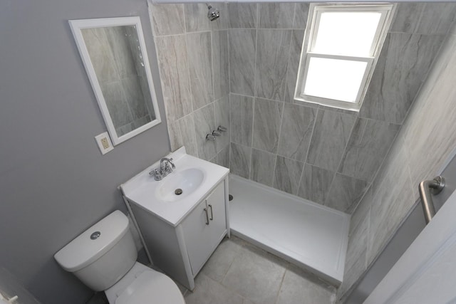 bathroom with a tile shower, vanity, and toilet