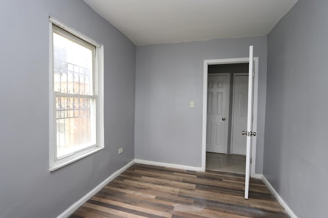 unfurnished bedroom with multiple windows and dark hardwood / wood-style floors