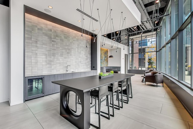 dining room featuring a high ceiling, light tile patterned flooring, and sink