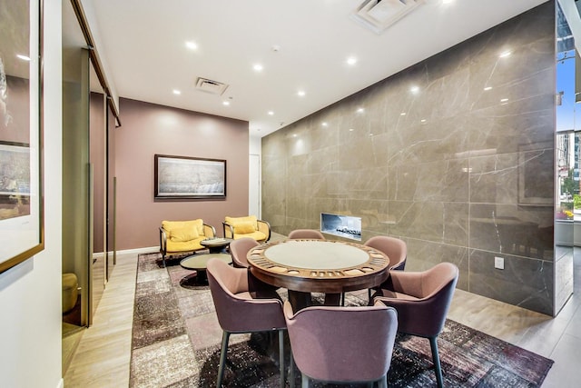 dining space with tile walls and light hardwood / wood-style flooring