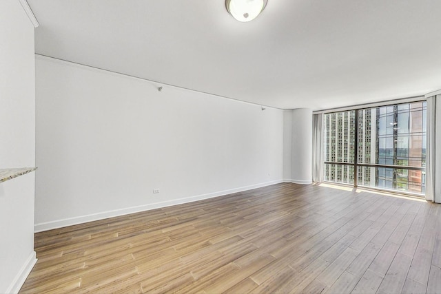 unfurnished room with a wall of windows and light wood-type flooring