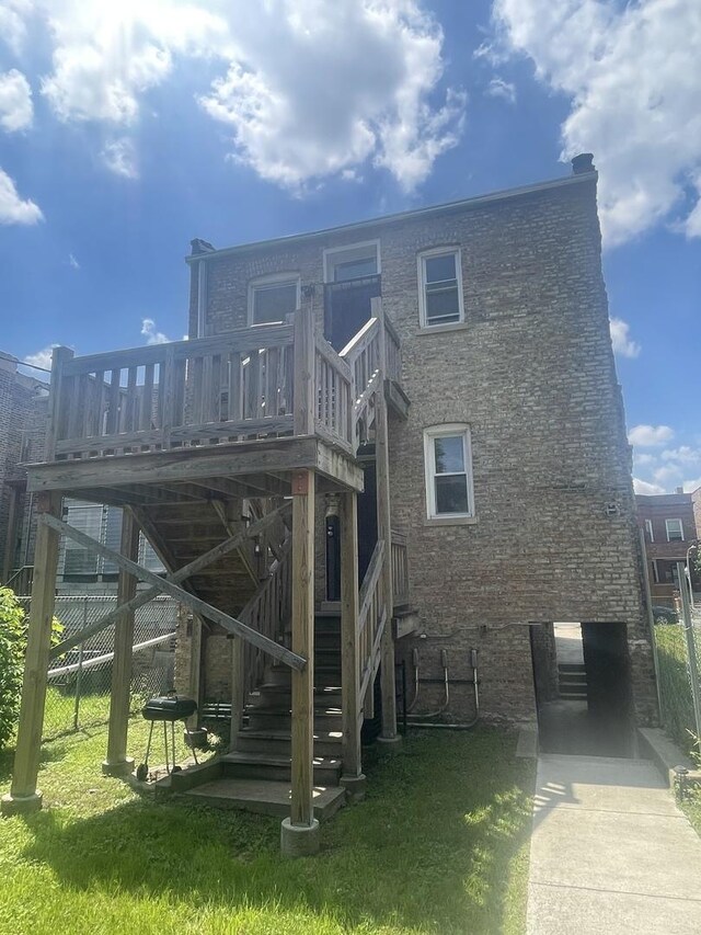 back of property with a yard and a wooden deck