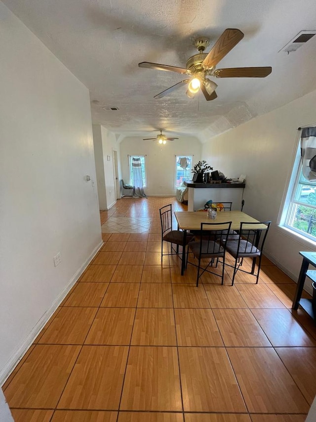 dining area with a textured ceiling, ceiling fan, and lofted ceiling