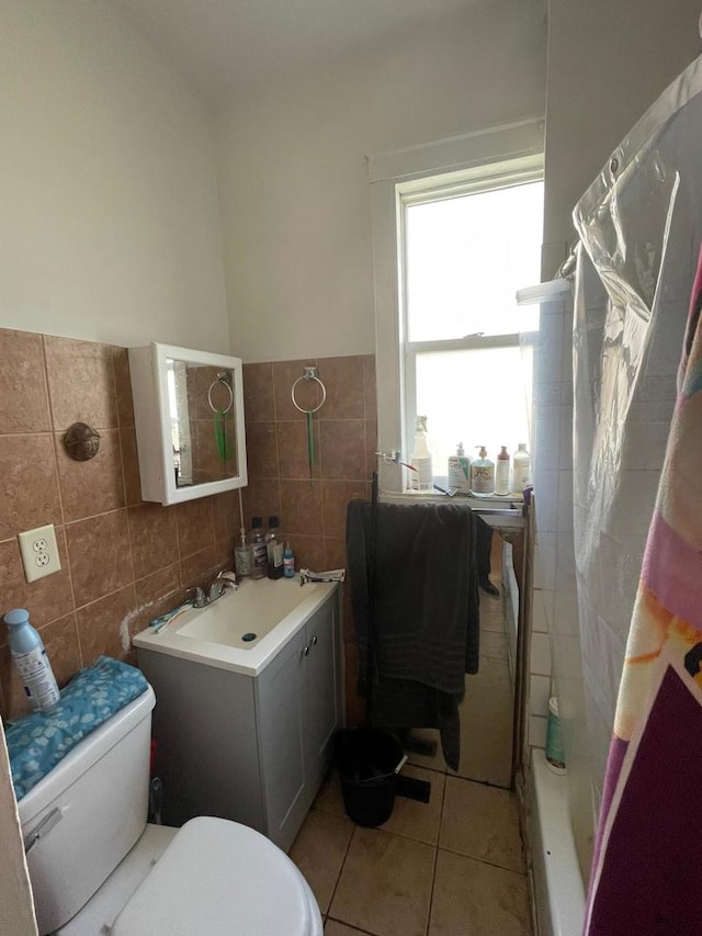 bathroom featuring tile patterned floors, toilet, tile walls, and walk in shower