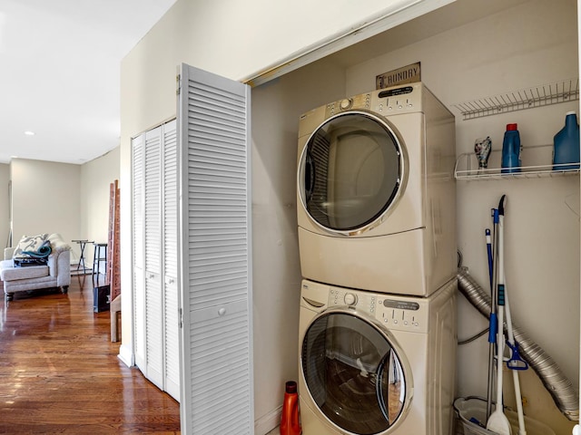 washroom with stacked washing maching and dryer and dark hardwood / wood-style floors