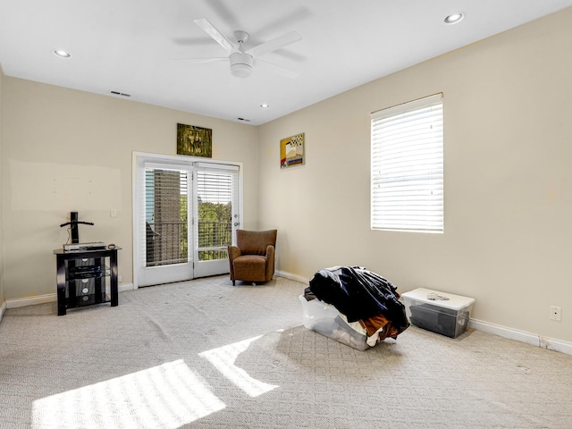 sitting room featuring light carpet, plenty of natural light, and ceiling fan