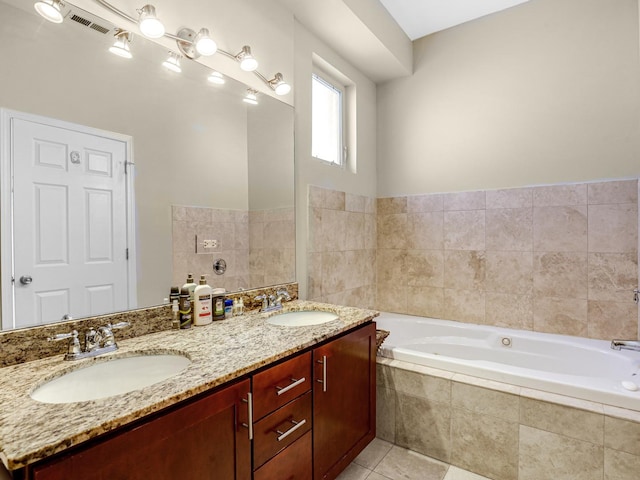 bathroom featuring tile patterned floors, vanity, and tiled bath