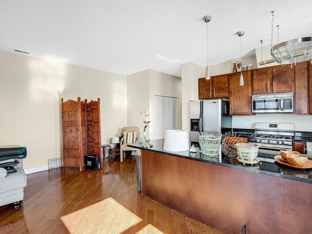 kitchen featuring pendant lighting, dark hardwood / wood-style floors, dark stone countertops, and appliances with stainless steel finishes