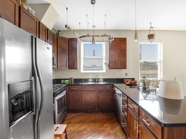 kitchen with dark wood-type flooring, pendant lighting, stainless steel appliances, and sink