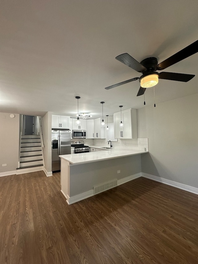 kitchen with white cabinets, sink, dark hardwood / wood-style floors, appliances with stainless steel finishes, and kitchen peninsula