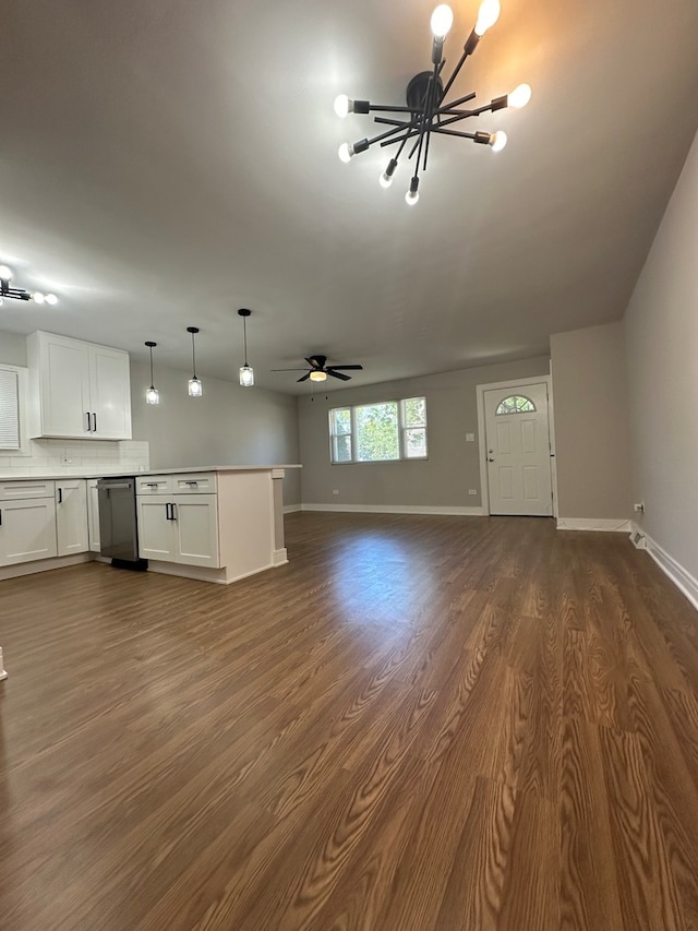 unfurnished living room with ceiling fan with notable chandelier and dark wood-type flooring