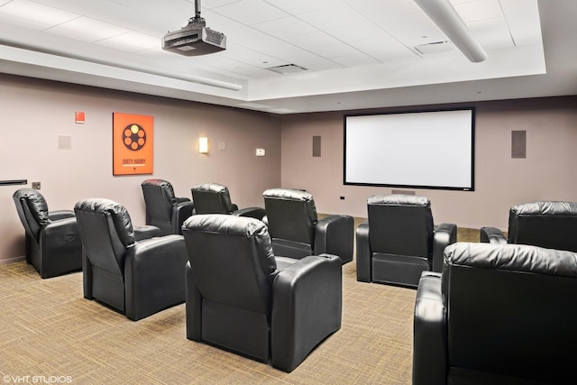 home theater room with a raised ceiling and light colored carpet