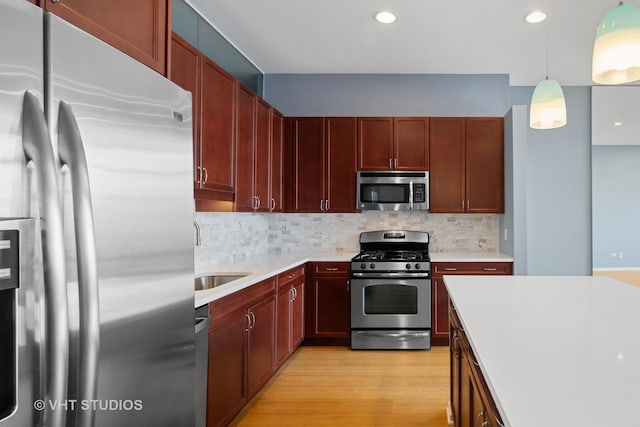 kitchen with decorative backsplash, sink, decorative light fixtures, and appliances with stainless steel finishes