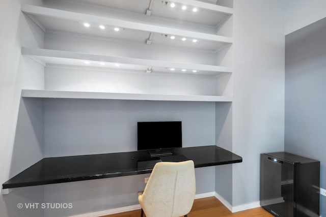 office space with built in shelves, built in desk, and hardwood / wood-style floors