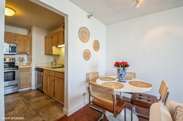 kitchen with stainless steel appliances, sink, dark tile floors, and a textured ceiling