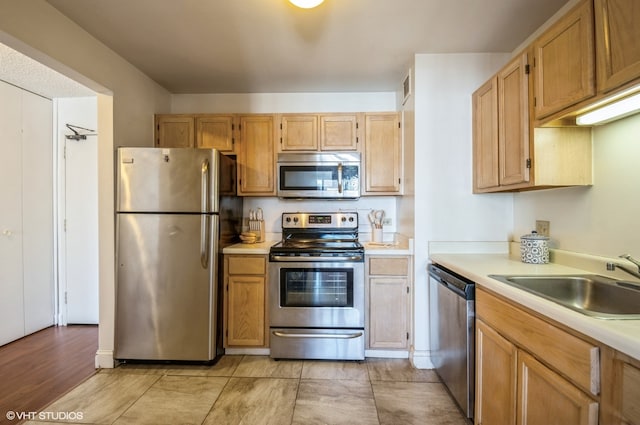 kitchen with sink, light tile flooring, and stainless steel appliances