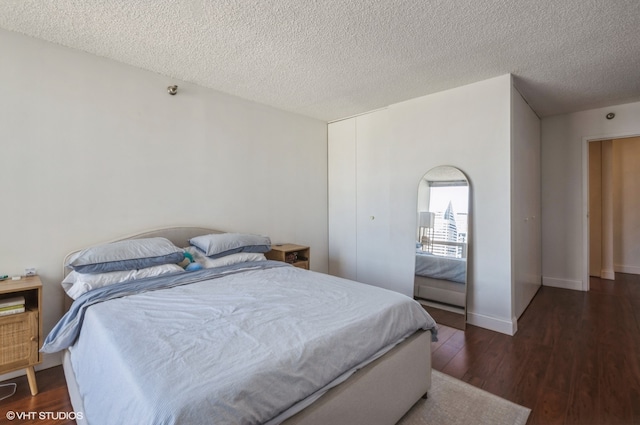 bedroom featuring a textured ceiling and dark hardwood / wood-style flooring