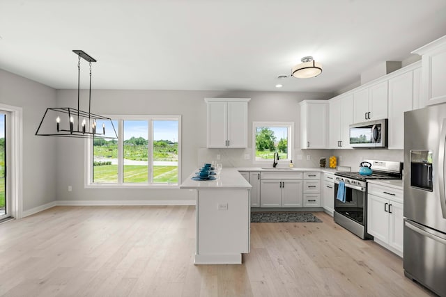 kitchen featuring light hardwood / wood-style flooring, tasteful backsplash, decorative light fixtures, sink, and appliances with stainless steel finishes