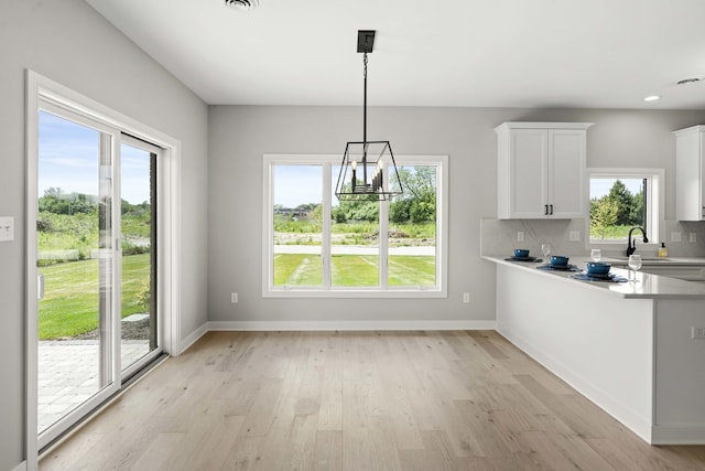 unfurnished dining area with an inviting chandelier, light wood finished floors, and plenty of natural light