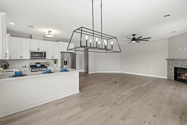 kitchen featuring a sink, light wood-style flooring, appliances with stainless steel finishes, and ceiling fan with notable chandelier