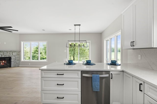 kitchen featuring a peninsula, open floor plan, light stone countertops, and dishwasher