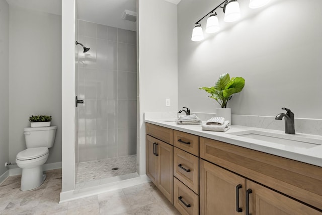 bathroom featuring toilet, tiled shower, a sink, and visible vents