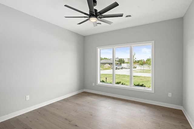 spare room featuring baseboards, ceiling fan, wood finished floors, and visible vents