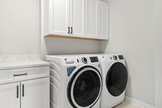 clothes washing area featuring separate washer and dryer, cabinet space, baseboards, and light tile patterned flooring