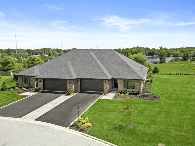 view of front facade with a water view, an attached garage, brick siding, and a front yard