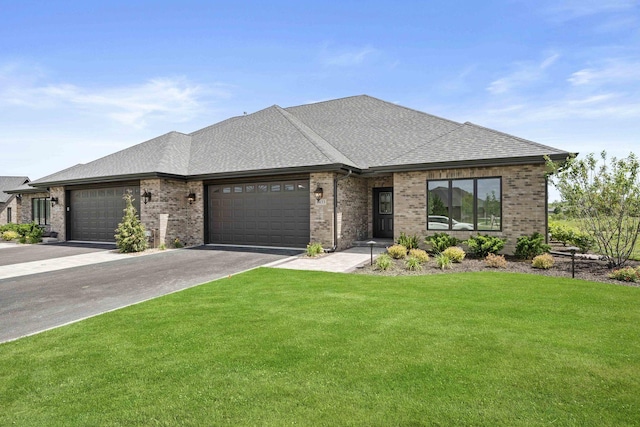 view of front facade featuring roof with shingles, a front lawn, brick siding, a garage, and aphalt driveway