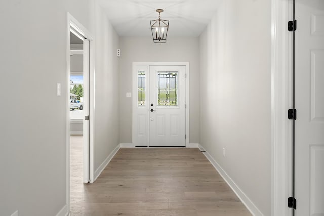 entryway with light wood-style floors, baseboards, and a notable chandelier