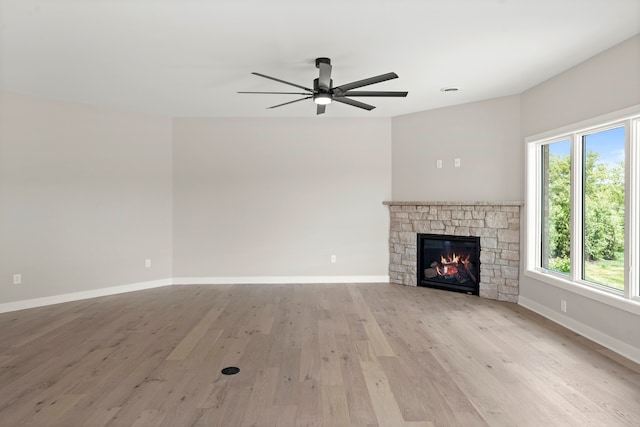 unfurnished living room with light hardwood / wood-style floors, a wealth of natural light, a fireplace, and ceiling fan