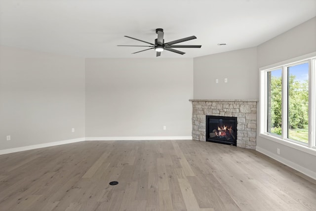 unfurnished living room featuring light wood-style floors, baseboards, a ceiling fan, and a wealth of natural light