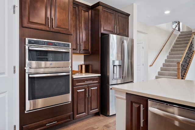 kitchen featuring appliances with stainless steel finishes, dark brown cabinets, and light hardwood / wood-style floors