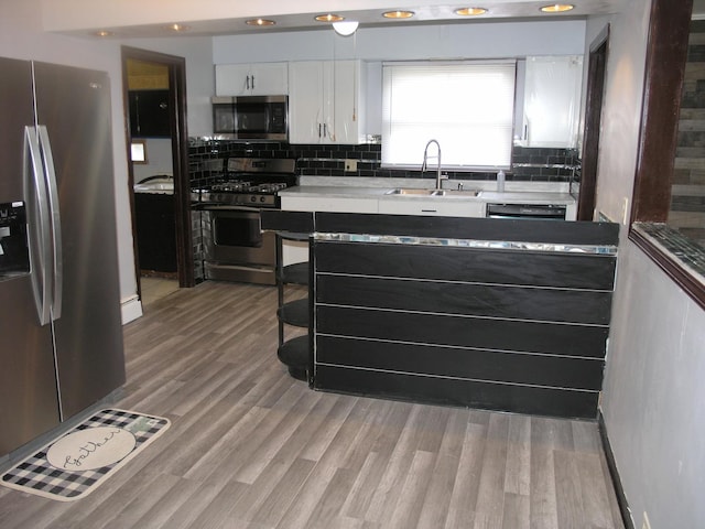 kitchen featuring white cabinets, light wood-type flooring, stainless steel appliances, and sink