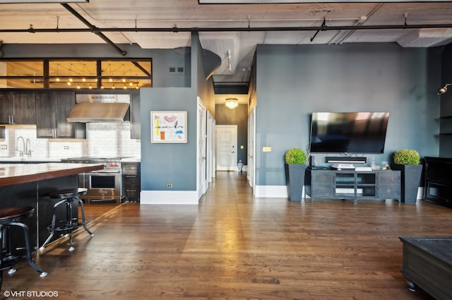 living room with a towering ceiling, hardwood / wood-style flooring, and sink