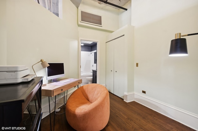 sitting room featuring a towering ceiling and dark wood-type flooring