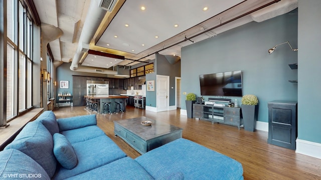 living room with a towering ceiling and light wood-type flooring