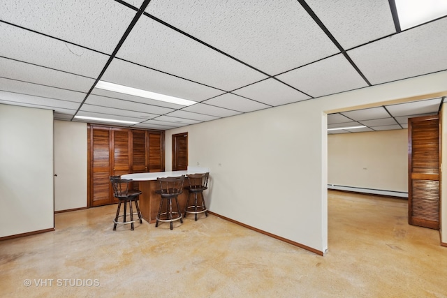 carpeted dining room with baseboard heating, a paneled ceiling, and bar